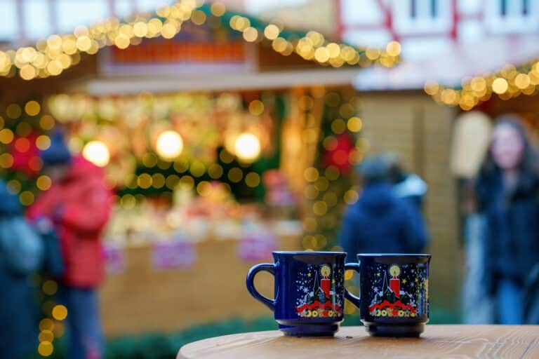 Two christmas cups with christmas markets in background